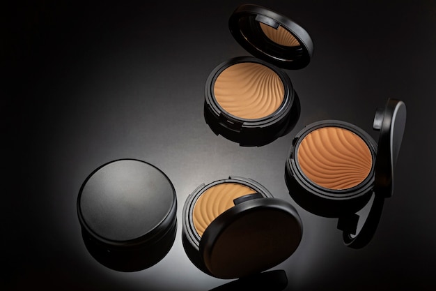 Professional makeup cosmetics compact powders on black.