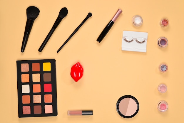 Professional makeup products with cosmetic beauty products, eye shadows, pigments, lipsticks, brushes and tools on beige background. Space for text or design.