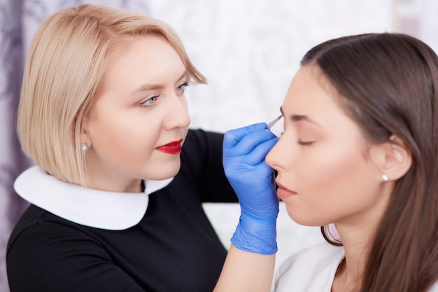 Photo professional making permanent make up for client in salon.