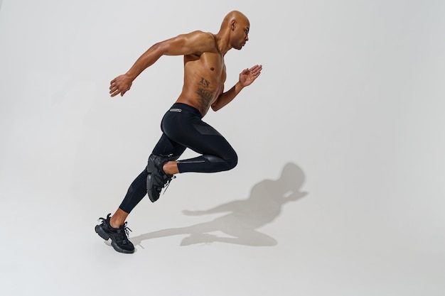 Professional male athlete running isolated on white studio background with shadows