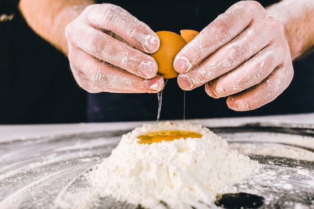 Professional male baker cooking dough with eggs