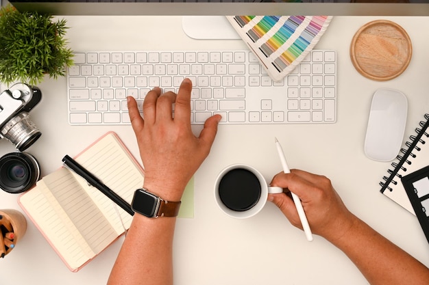 Professional male graphic designer sipping coffee while working typing on keyboard computer