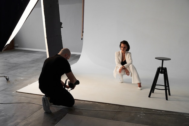 Photo professional male photographer taking pictures of beautiful woman model on camera in a studio