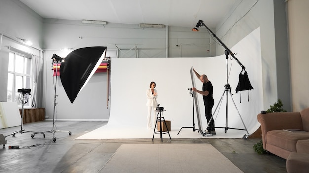 Professional male photographer taking pictures of beautiful woman model on camera in a studio