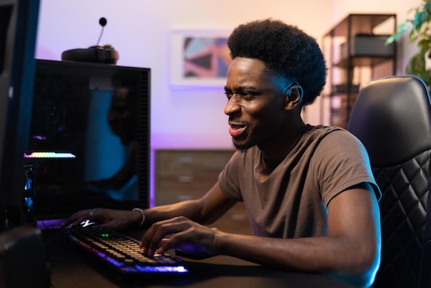 Professional male pro gamer sits comfortably in chair leaning over computer playing video games