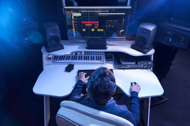 レコーディングスタジオでオーディオをミキシングするプロの男性サウンドエンジニア。ミキサーに取り組んでいる音楽制作技術