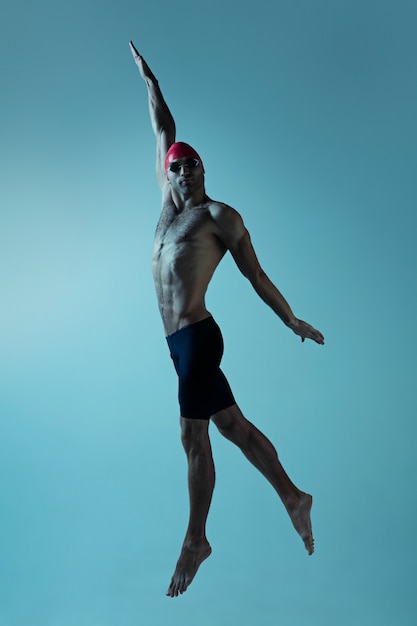 Professional male swimmer with hat and goggles in motion and action