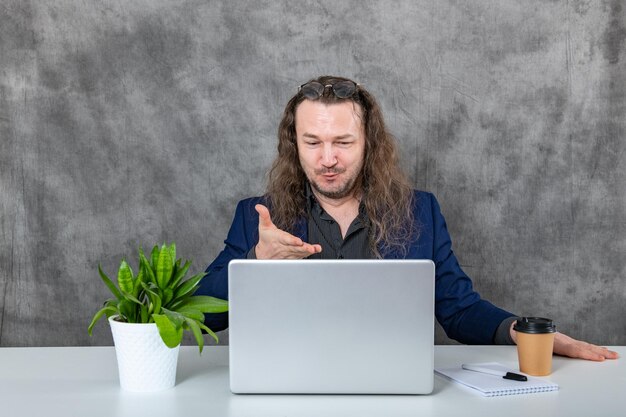 近代的なオフィス環境でラップトップで勤勉に働く長のプロの男性