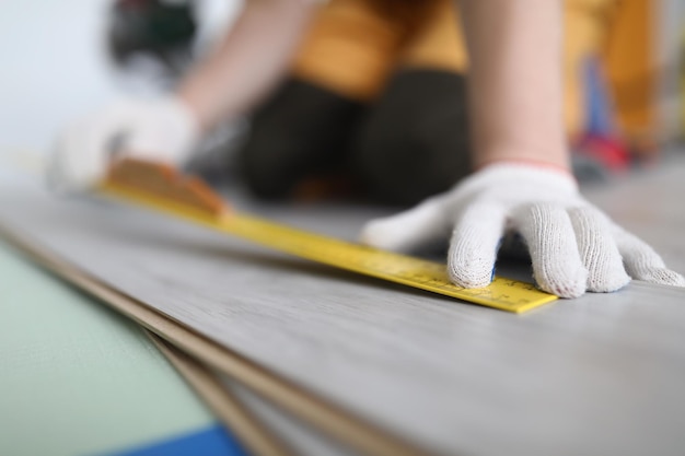 Professional male worker apply tape measure on wooden plank for further cutting