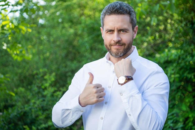 Professional man giving thumbs up showing wristwatch natural background punctuality