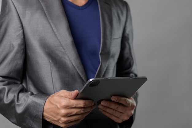 professional man in suit holding tablet with gray background