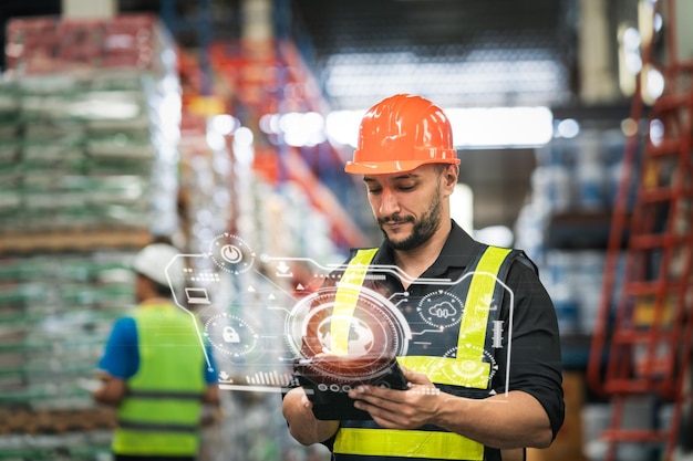 Professional manager man employee using tablet check stock working at warehouse Worker wearing high visibility clothing and a hard hat helmet and checking and count up goods or boxes for delivery
