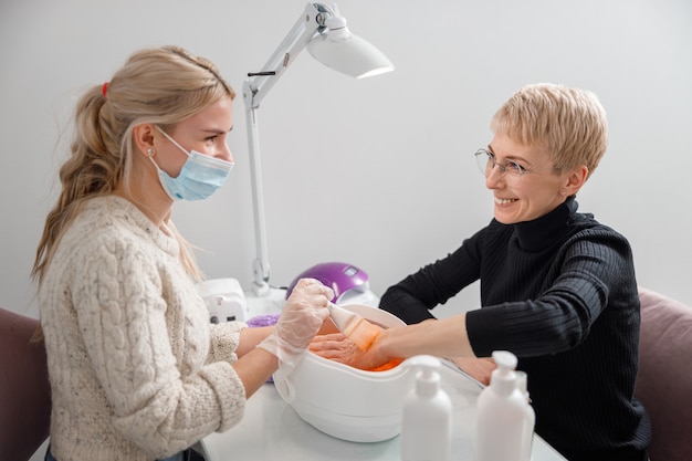 Professional manicure master is doing nails for client in beauty salon