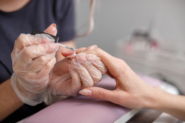 Il maestro di manicure professionale sta facendo le unghie per il cliente nel salone di bellezza