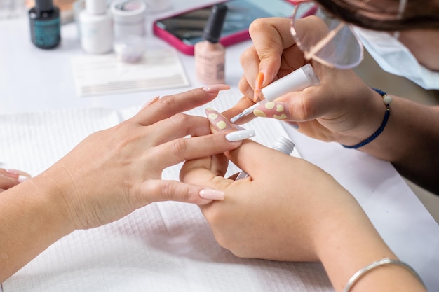 Professional manicurist applying white polish on a woman's nails