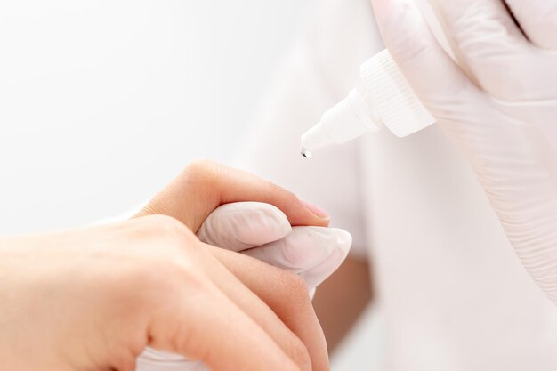 Professional manicurist pouring oil on nails manicure of woman in beauty salon.