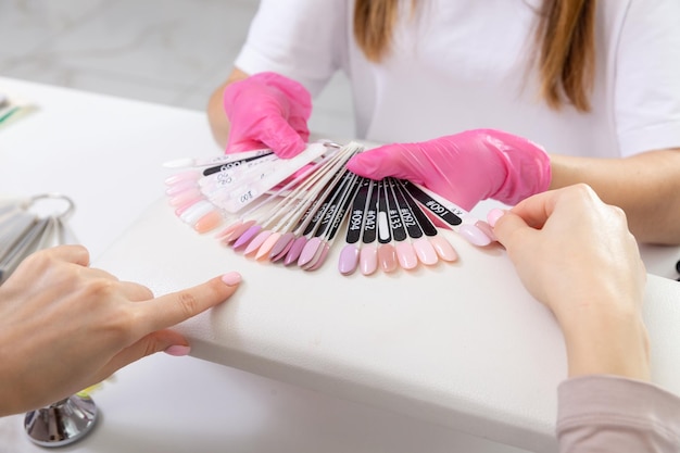 Professional manicurist showing colorful nail polish to check the finish result