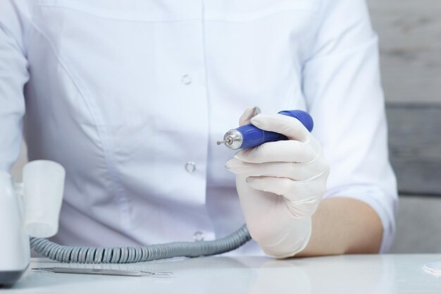 Professional manicurist switch on nail drill in nail beauty salon