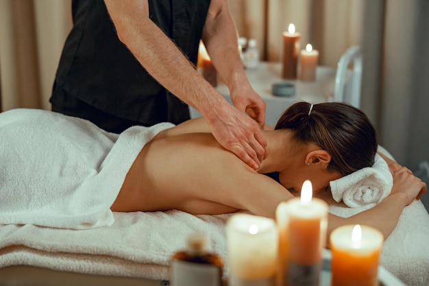 Professional masseur man doing back massage for female client\
at spa center relaxation therapy