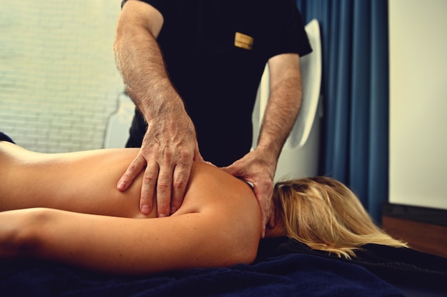 Professional masseur working with the back of a wellness spa center client. Remedial and therapeutic professional massage of woman's back