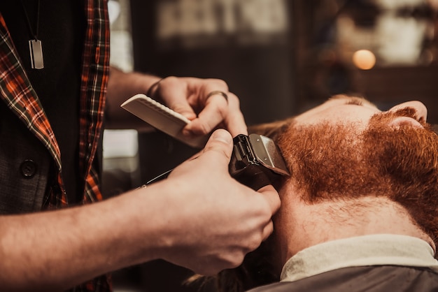 Professional Master hairdresser cuts client beard.