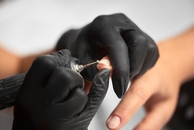 Professional master manicurist working on client fingernails