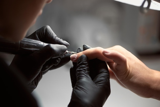 Professional master manicurist working on client fingernails