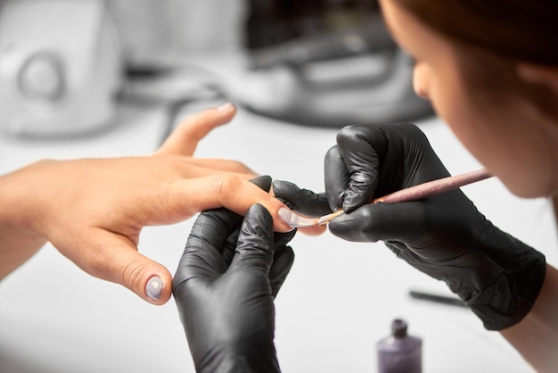 Professional master manicurist working on client fingernails