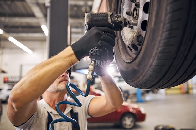 Professional mechanic repairing car wheel disk in garage