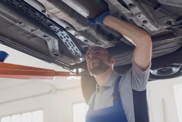 Professional mechanic working under a car in a repair shop car maintenance and repair concept