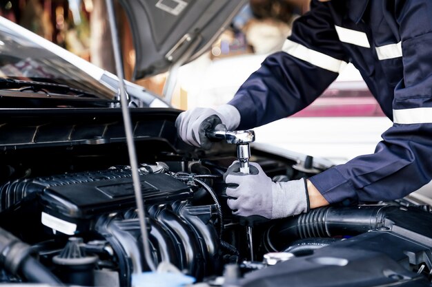 Professional mechanic working on the engine of the car in the\
garage car repair service