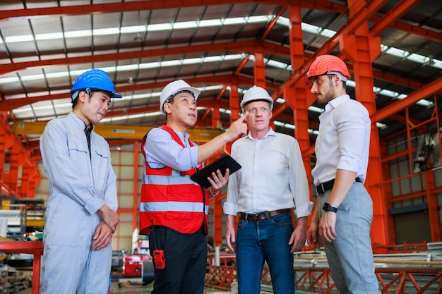 Professional mechanical engineer team working on personal\
computer at metal sheet industrial manufacturing factory product\
quality inspection worker in safety hardhat at factory\
industrial