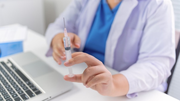 바이러스 covid19에 대한 건강 약물 예방 접종 인플루엔자 싸움을 주입하는 손 백신에 주사기 의료 주입을 가진 전문 의료 아시아 여성 의사