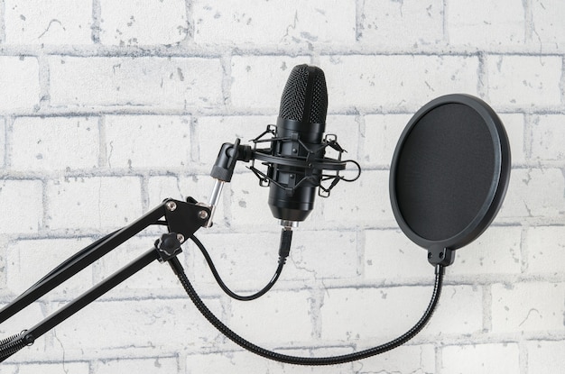 Professional microphone for sound recording on the background of a light brick wall