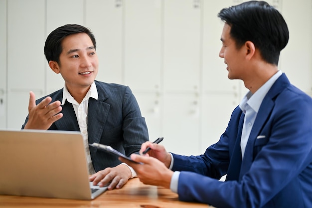 A professional millennial Asian businesswoman is talking with his colleague