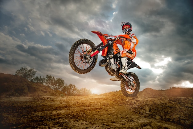 Photo professional motorcycle rider driving on the mountains and further down the off-road track.