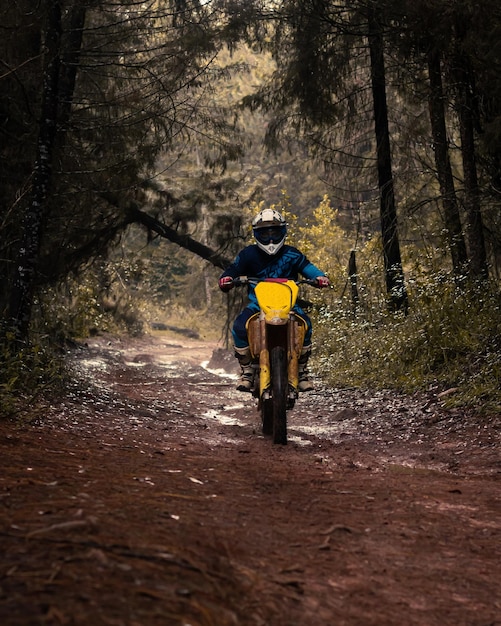 숲의 전문 오토바이 라이더는 자연 도로의 진흙을 통과합니다