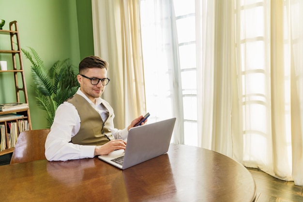 Professional multitasking with phone and laptop at a bright wooden table