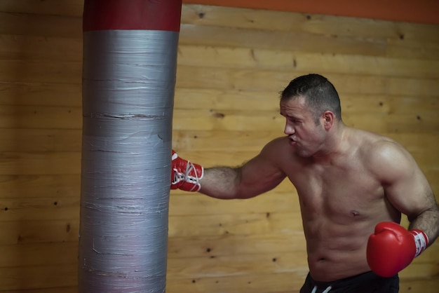 professional muscular kick boxer training on a punching bag while preparing for the next fight