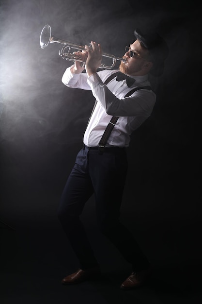 professional musician playing trumpet on black background with smoke