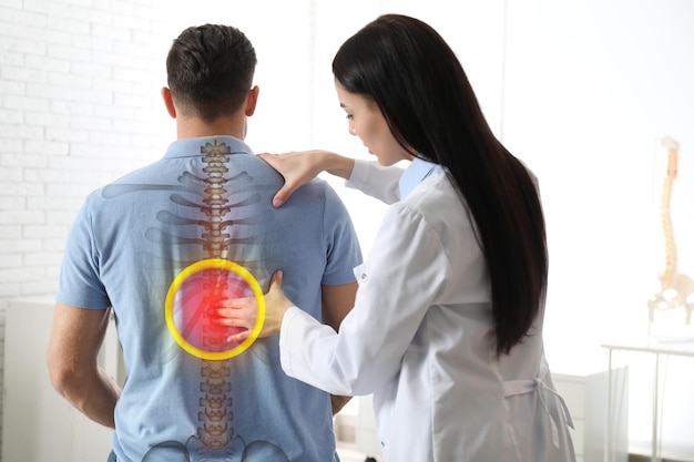 Photo professional orthopedist examining man in medical office spinal pain