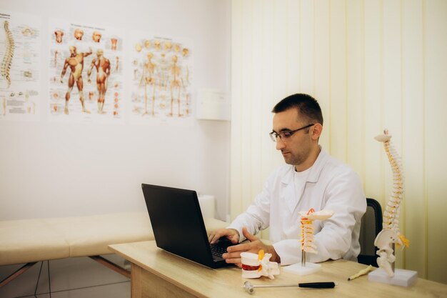 Professional orthopedist at table in medical office