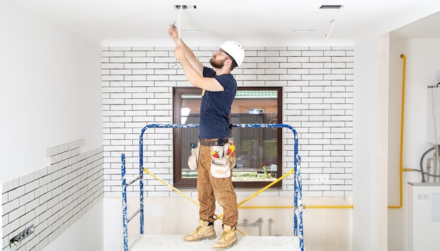 Professional in overalls with tools on the repair site full length. Home renovation concept.