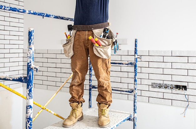 Professional in overalls with tools on the repair site.