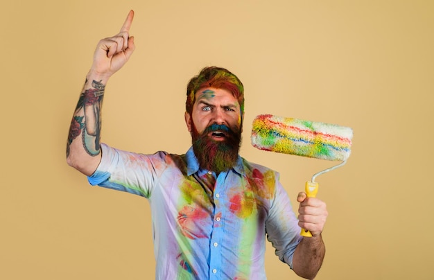 Professional painter decorator builder worker with paint roller pointing finger up bearded workman