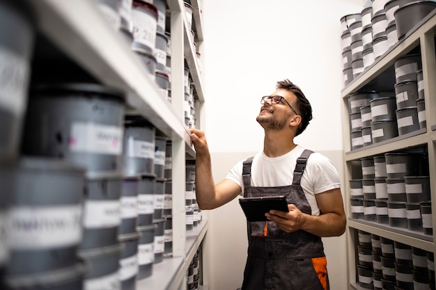 Professional painter looking for a can of paint in warehouse.