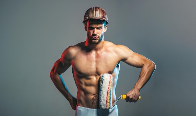 Professional painter with paint roller muscular man with paintroller builder in hardhat with