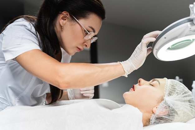 Professional permanent makeup artist and her client during lip blushing procedure