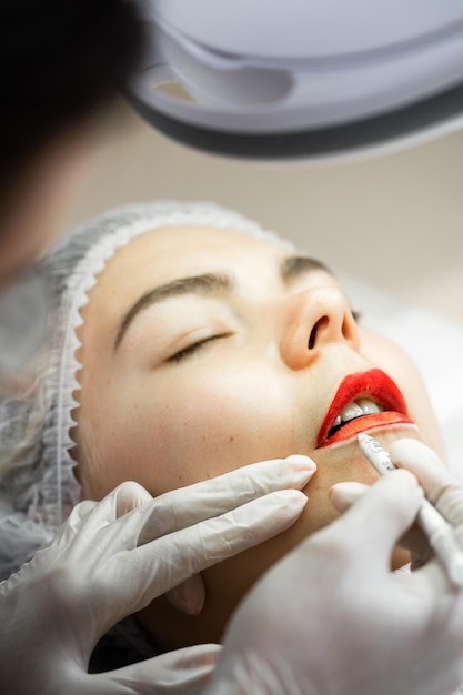 Professional permanent makeup artist and her client during lip blushing procedure