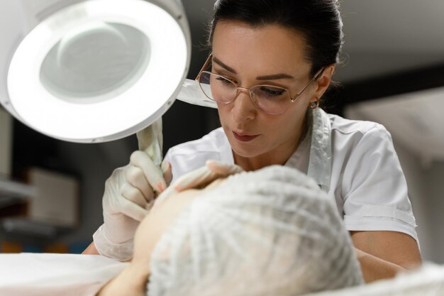 Профессиональный перманентный визажист и ее клиент во время процедуры окрашивания губ